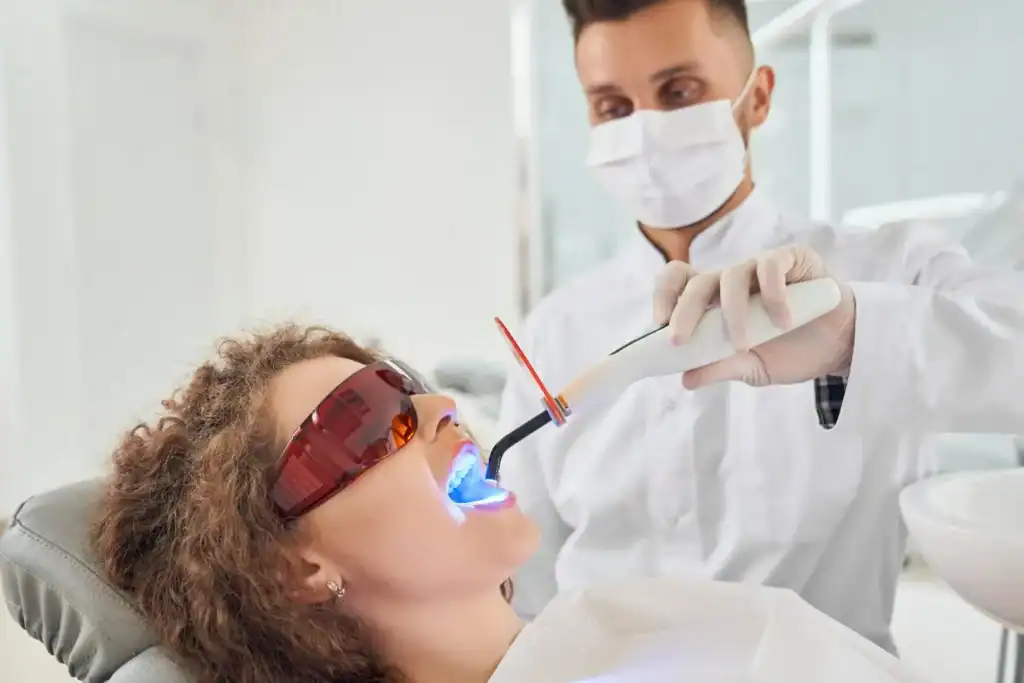 Woman receiving professional Laser Teeth Whitening treatment with safety glasses Buckhurst-Hill
